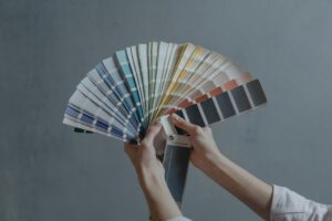 Hands holding a colorful fan of swatches on a gray backdrop, ideal for design themes.